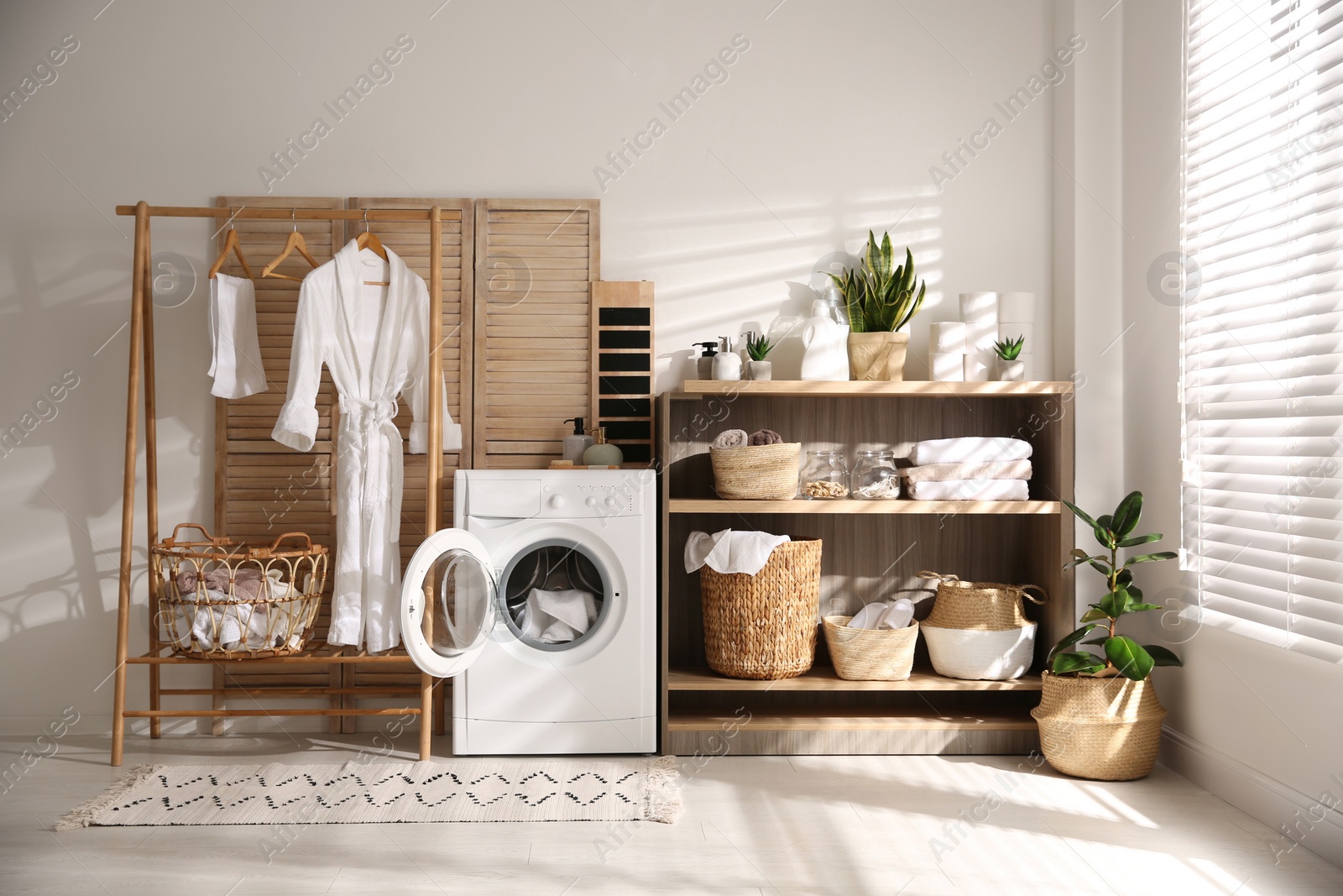 Photo of Modern washing machine and shelving unit in laundry room interior