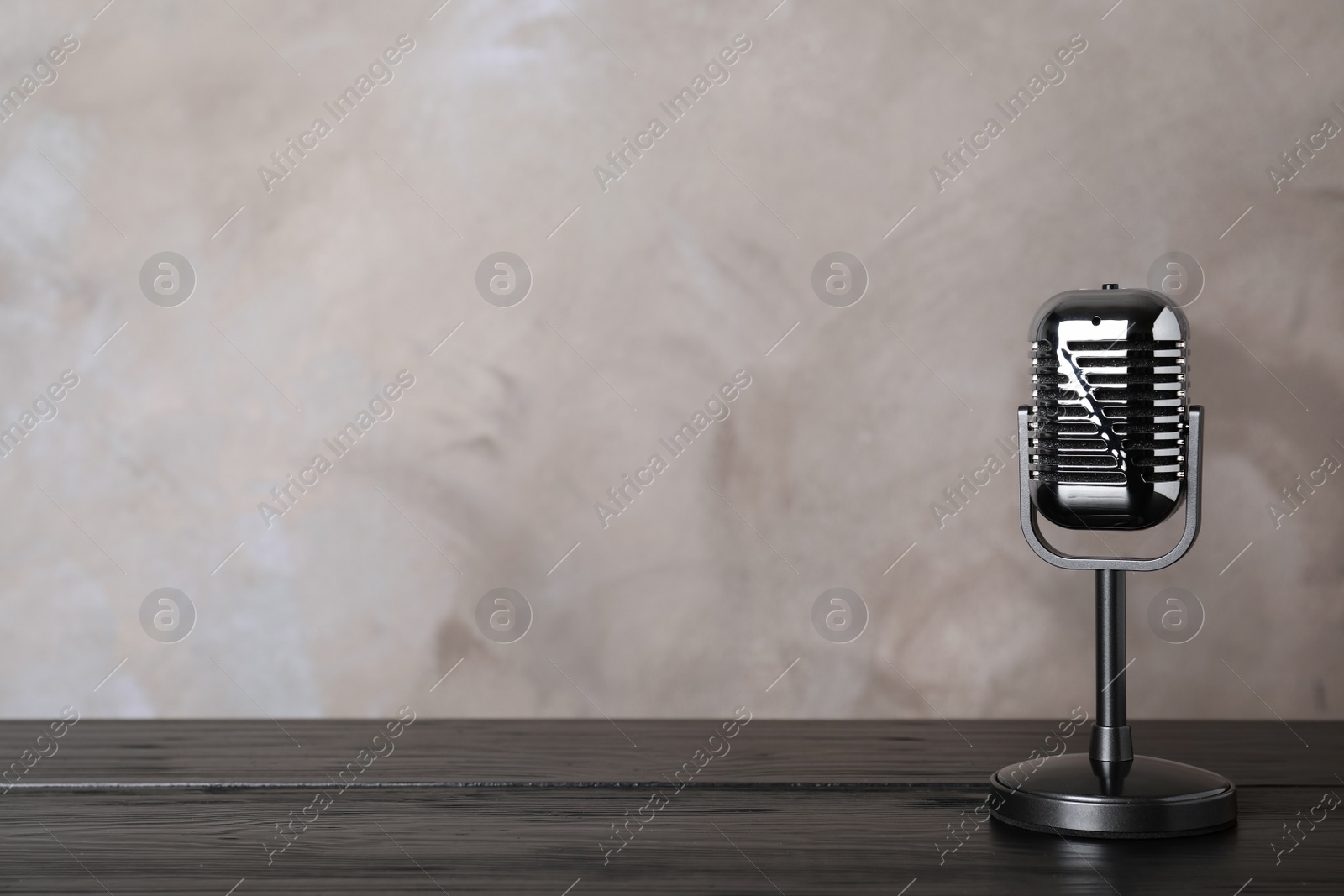 Photo of Retro microphone on table against color background. Space for text