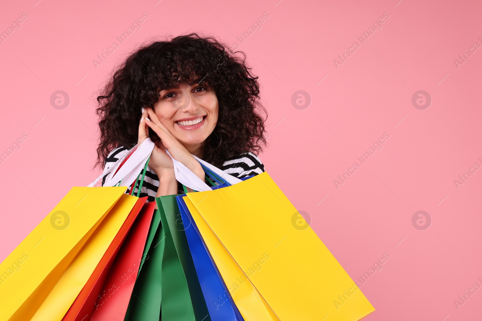 Photo of Happy young woman with shopping bags on pink background