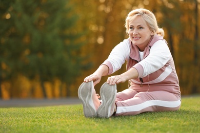 Photo of Happy mature woman stretching in park. Active lifestyle