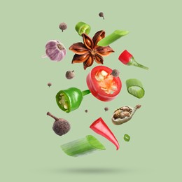 Image of Different spices falling on light green background