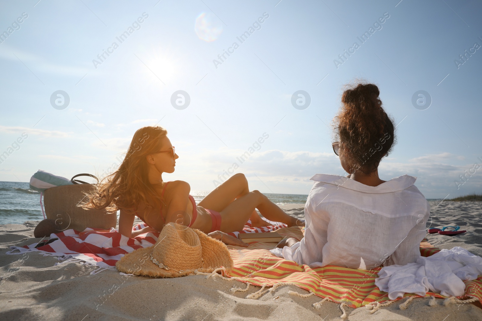 Photo of Friends lying on beach towels near sea