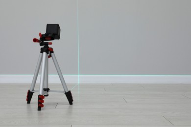 Photo of Cross line laser level on tripod in front of light wall indoors