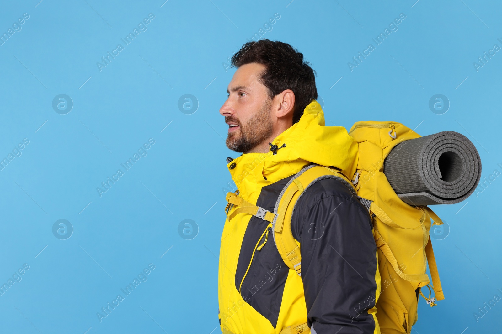 Photo of Man with backpack on light blue background, space for text. Active tourism