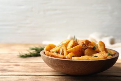 Photo of Plate with baked potatoes and rosemary on wooden table. Space for text