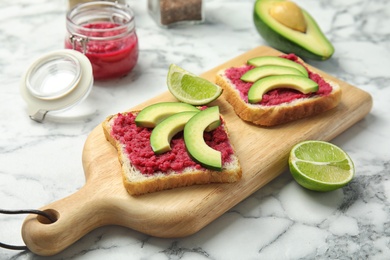 Photo of Crisp toasts with avocado and chrain on wooden board, closeup