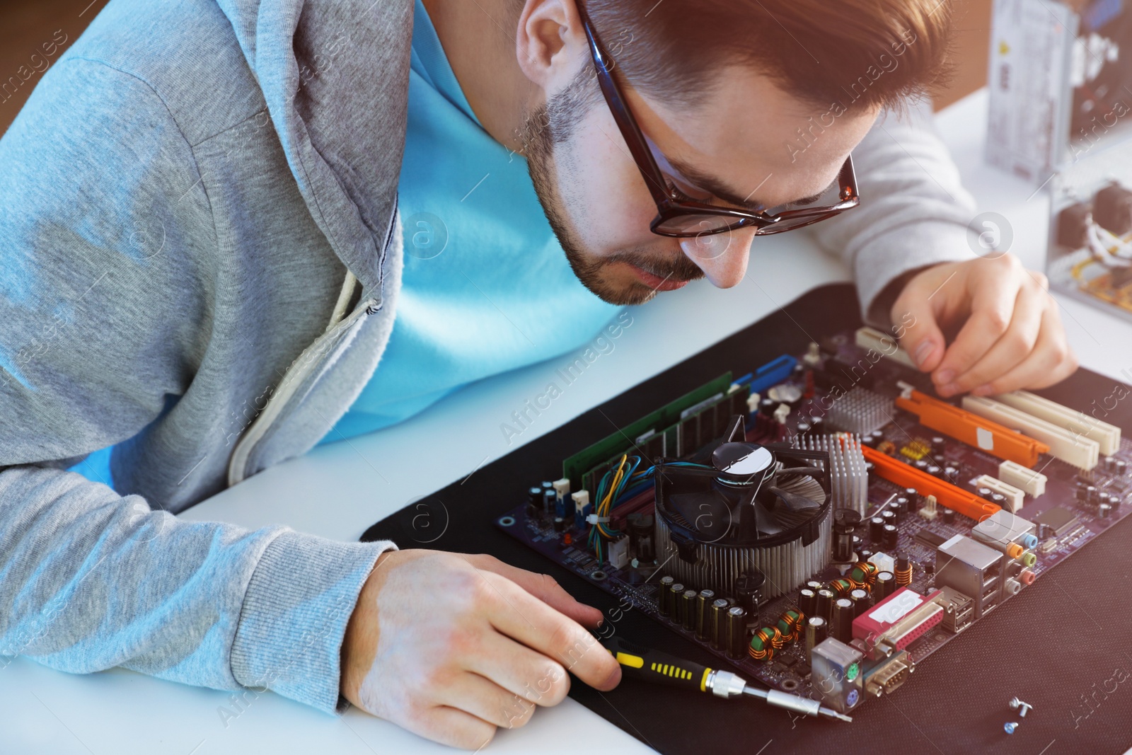 Photo of Male technician repairing computer motherboard at table