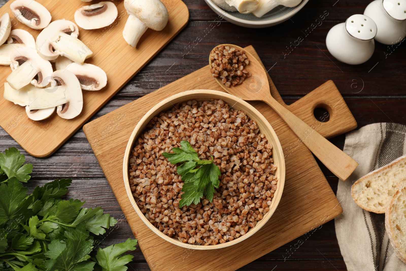 Photo of Tasty buckwheat with parsley in bowl served on wooden table, flat lay