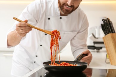 Photo of Professional chef cooking delicious spaghetti in frying pan indoors, closeup