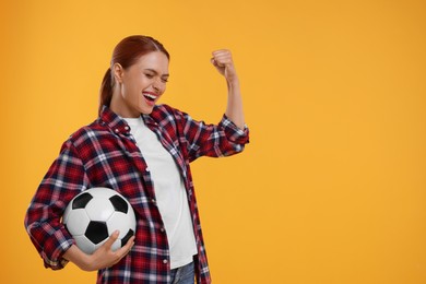 Happy fan holding football ball and celebrating on yellow background, space for text