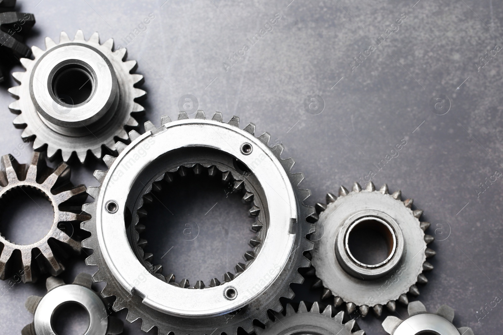 Photo of Different stainless steel gears on grey background, flat lay. Space for text