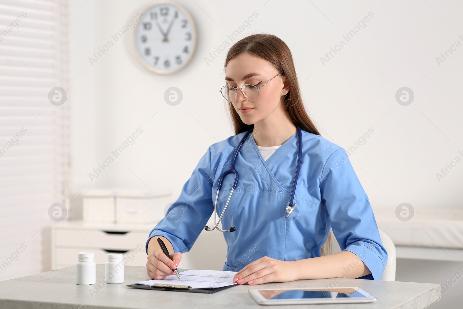 Photo of Doctor filling patient's medical card at table in clinic