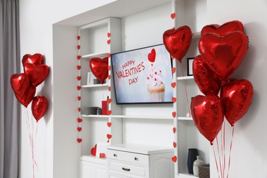 Photo of Cozy living room with modern TV and heart shaped balloons decorated for Valentine Day. Interior design