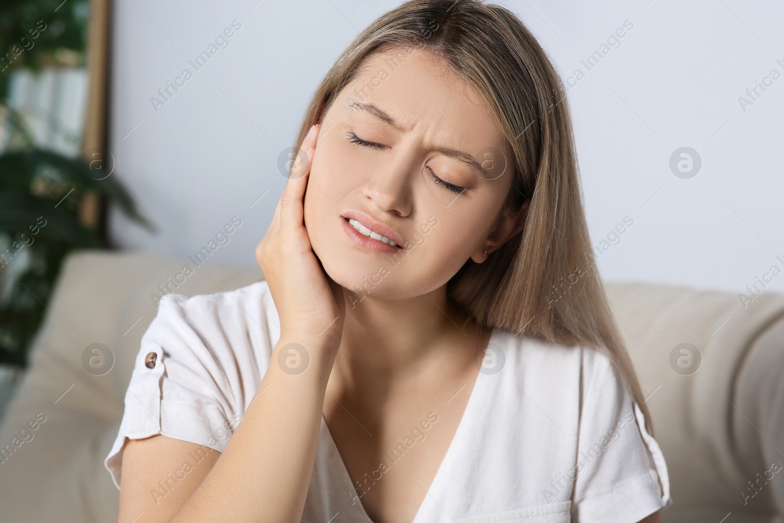 Photo of Young woman suffering from ear pain at home