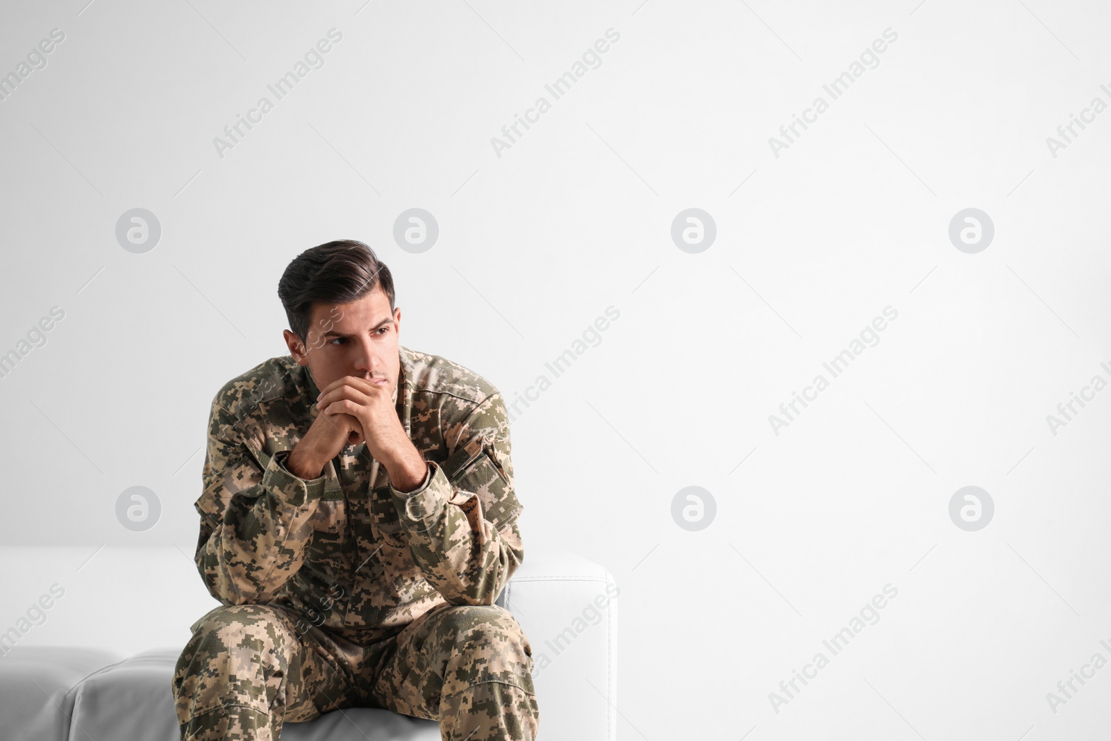 Photo of Stressed military officer sitting on sofa against white background. Space for text