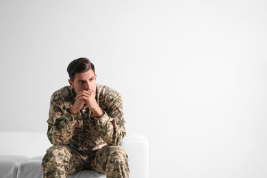 Photo of Stressed military officer sitting on sofa against white background. Space for text