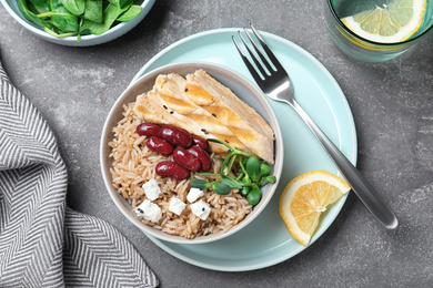 Photo of Tasty rice with beans served on grey table, flat lay