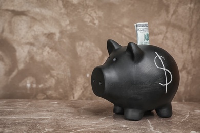 Photo of Black piggy bank with dollar symbol and money on table