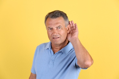 Photo of Mature man with hearing problem on color background