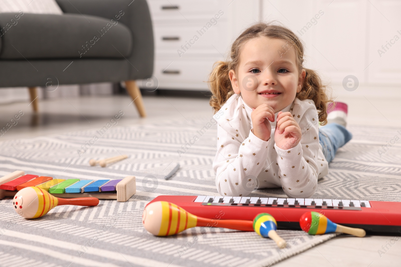 Photo of Little girl playing with toy musical instruments at home
