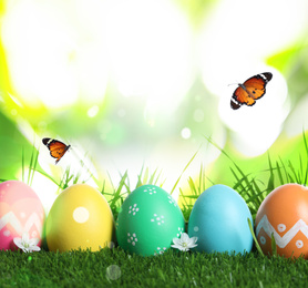 Image of Colorful Easter eggs and butterflies on blurred green background