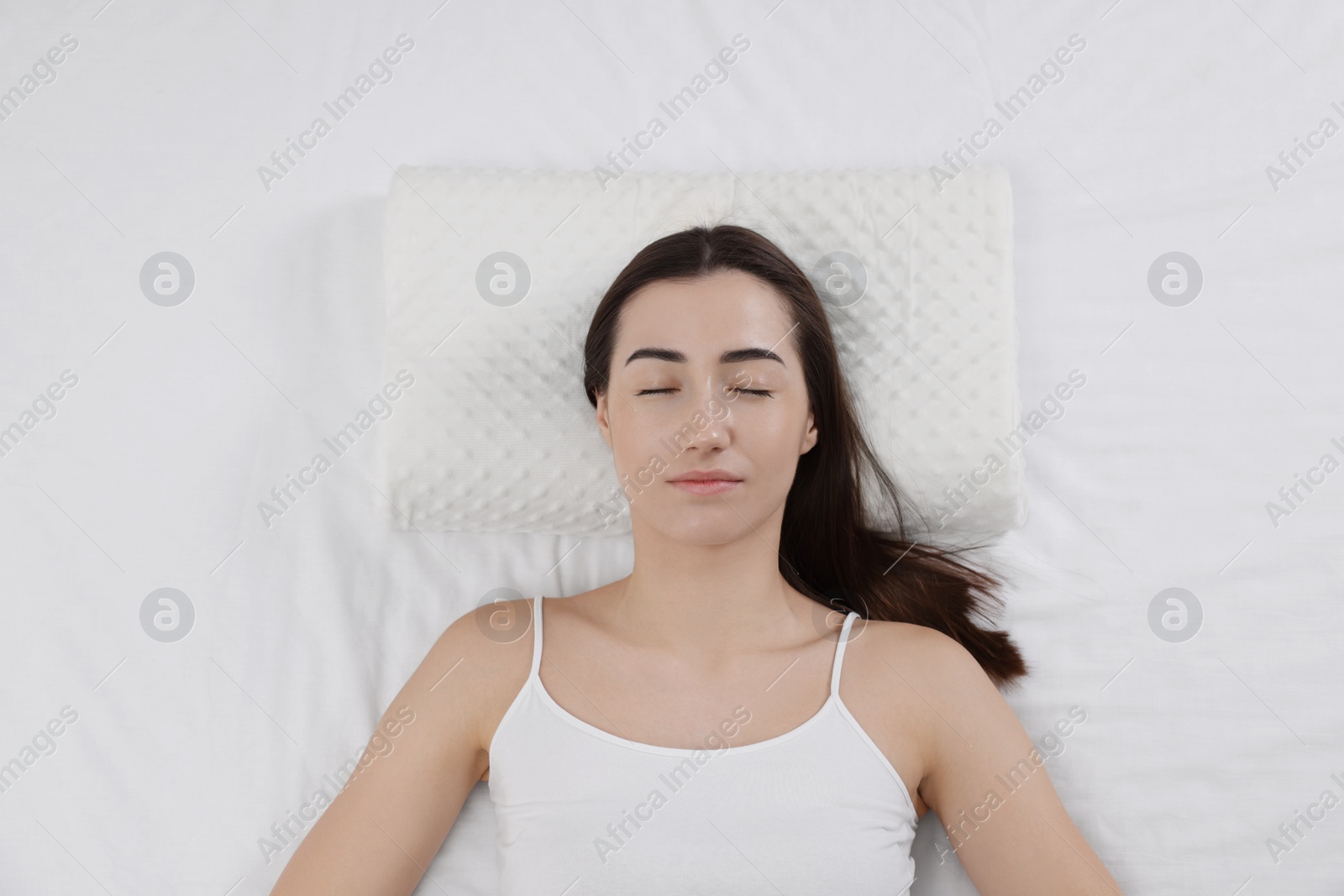 Photo of Woman sleeping on orthopedic pillow in bed, top view