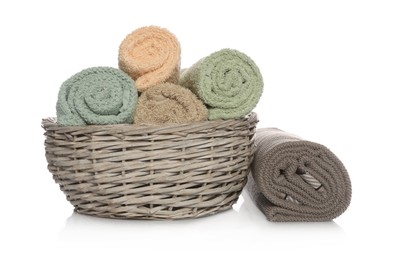Photo of Wicker basket with rolled towels on white background