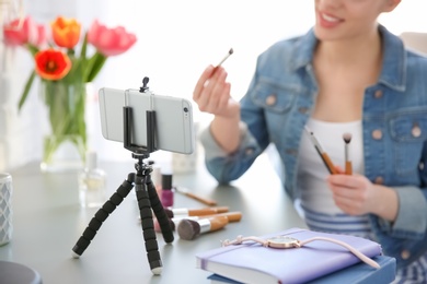 Photo of Young beauty blogger recording video at table