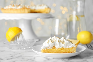 Photo of Plate with piece of delicious lemon meringue pie on white marble table