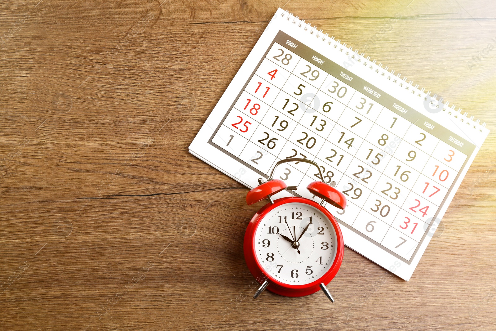 Image of Calendar and alarm clock on wooden table, flat lay. Space for text