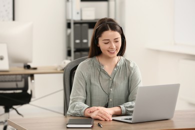 Photo of Hotline operator with headset working on laptop in office