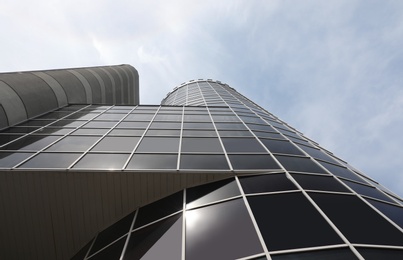 Modern building with tinted windows against sky, low angle view. Urban architecture