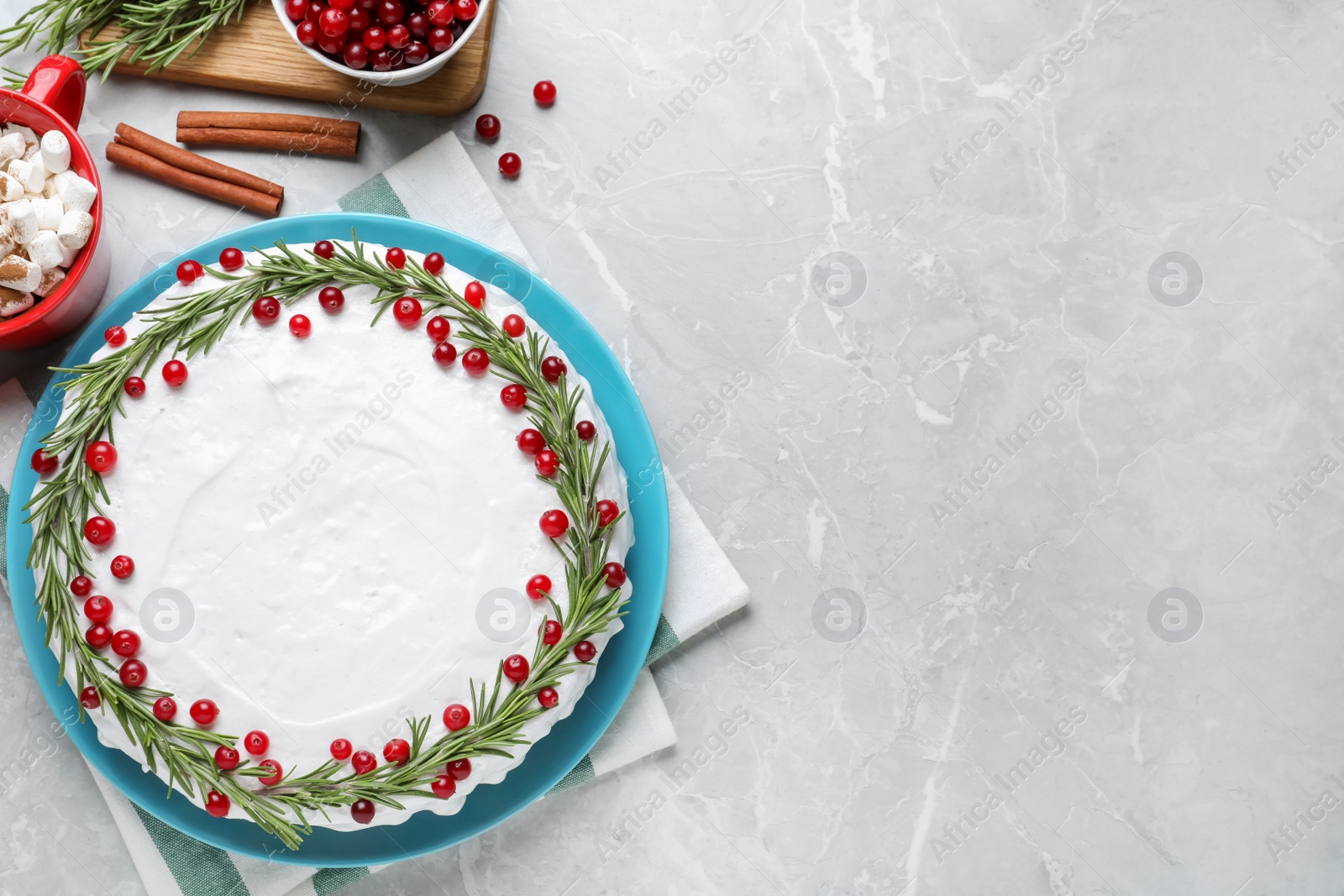 Photo of Traditional Christmas cake decorated with rosemary and cranberries on light grey marble table, flat lay. Space for text
