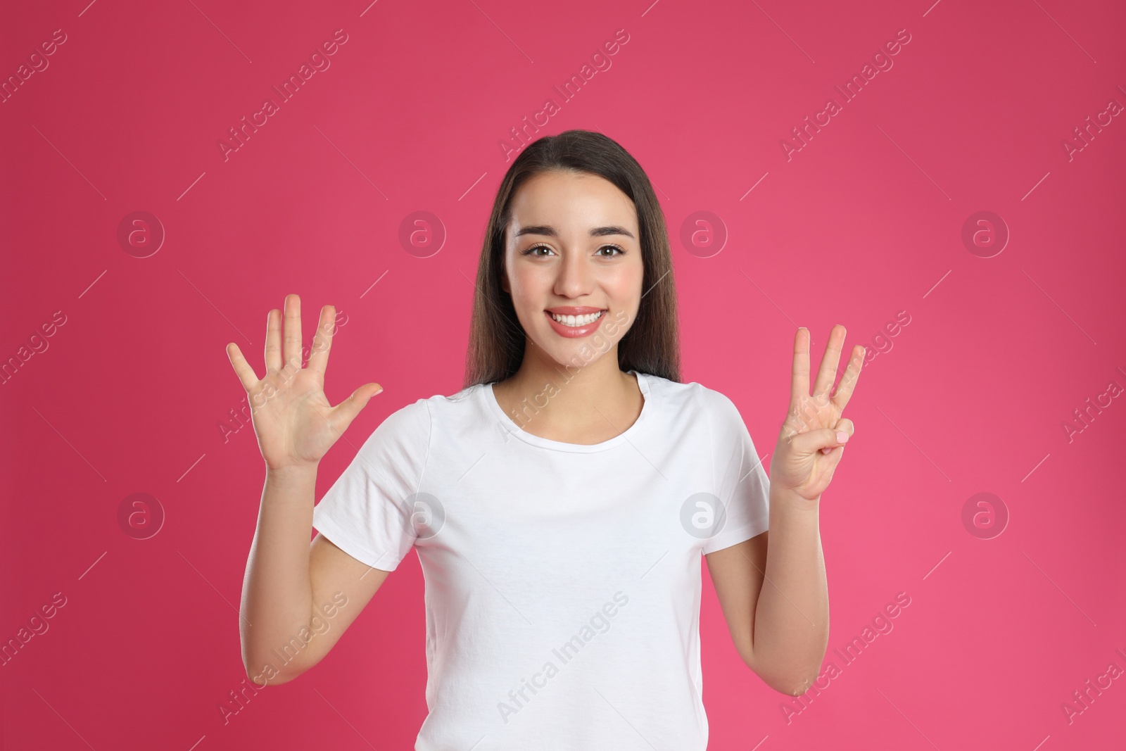 Photo of Woman showing number eight with her hands on pink background