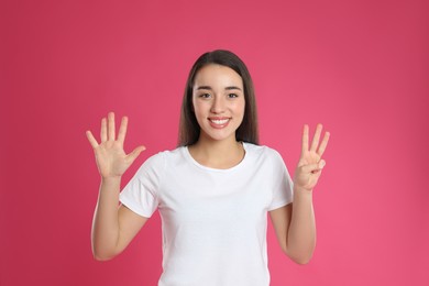 Photo of Woman showing number eight with her hands on pink background