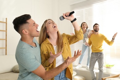 Happy couple singing karaoke with friends at home