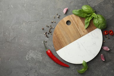 Photo of Cutting board, basil, pepper, chili peppers and garlic on grey table, flat lay. Space for text