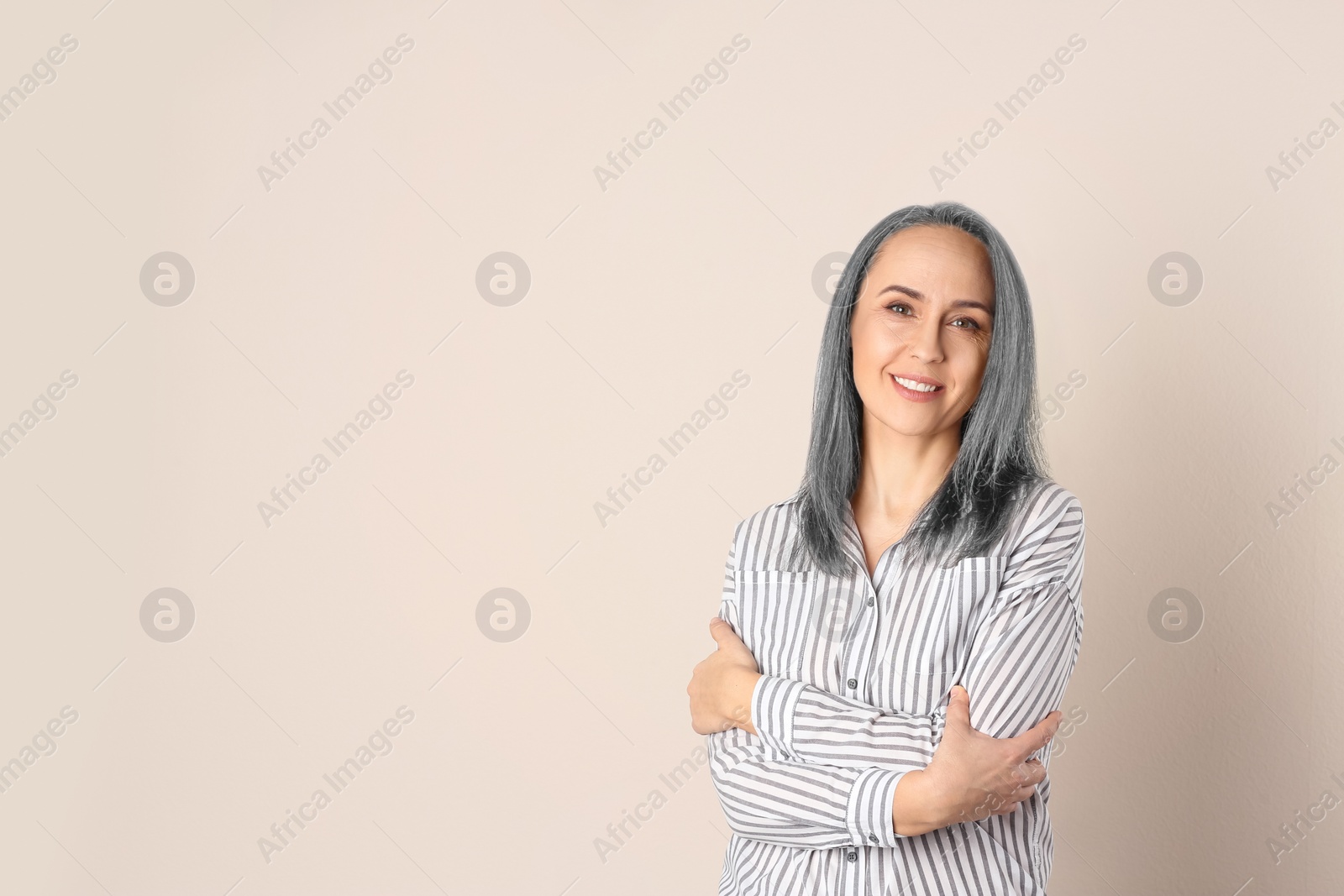 Image of Portrait of smiling woman with ash hair color on beige background. Space for text