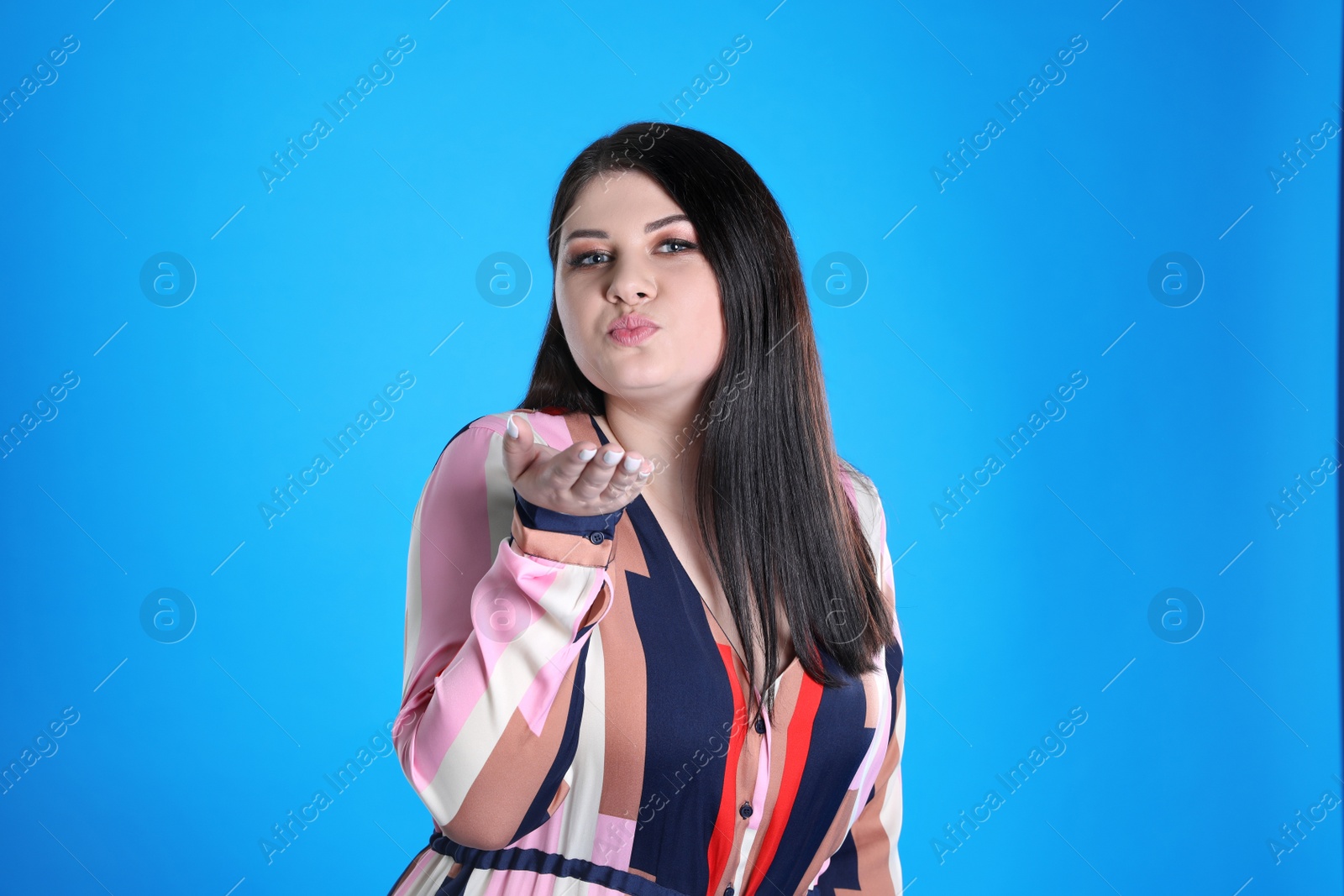 Photo of Beautiful overweight woman posing on light blue background. Plus size model