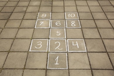 Photo of Hopscotch drawn with white chalk on street tiles outdoors