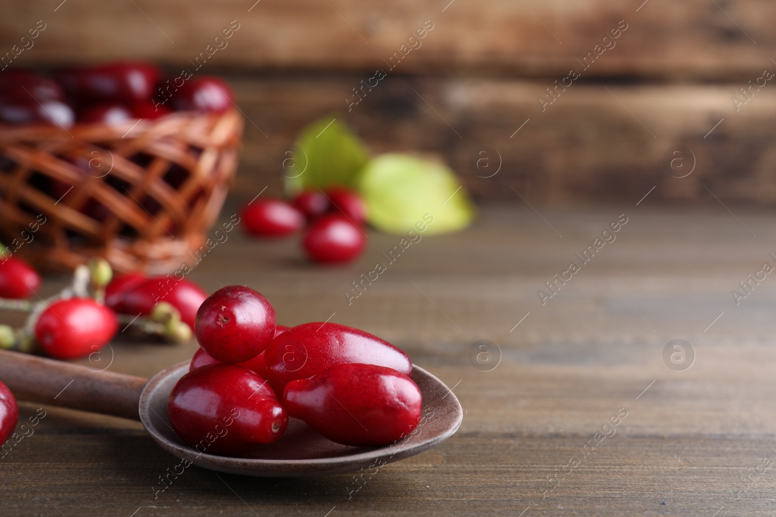 Photo of Fresh ripe dogwood berries with spoon on wooden table, closeup
