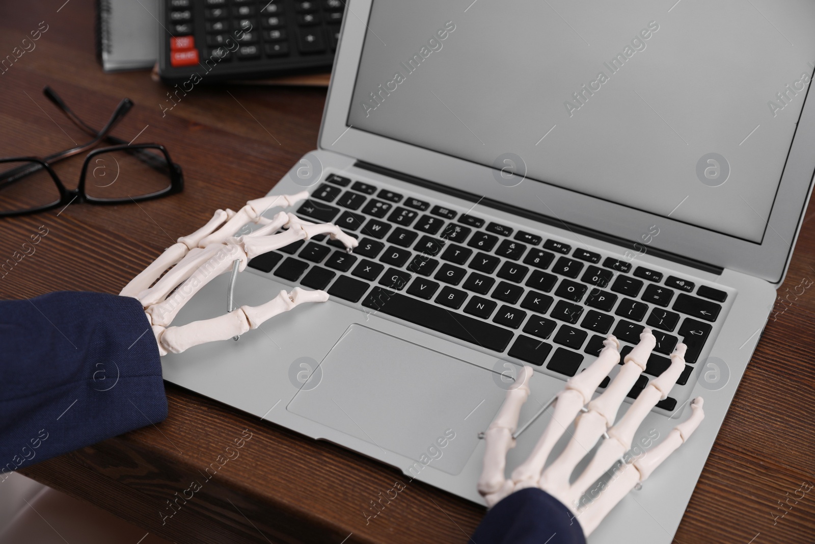 Photo of Human skeleton in suit using laptop at table, closeup