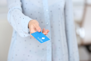 Woman holding business card indoors, closeup with space for text. Medical service