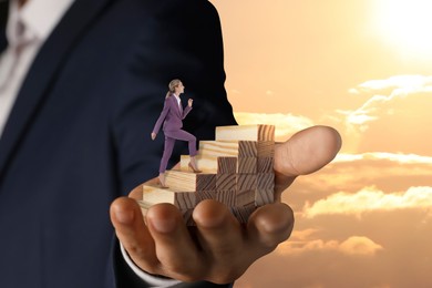 Image of Steps to success. Businesswoman climbing up stairs of wooden blocks. Man holding stairway in sky, closeup