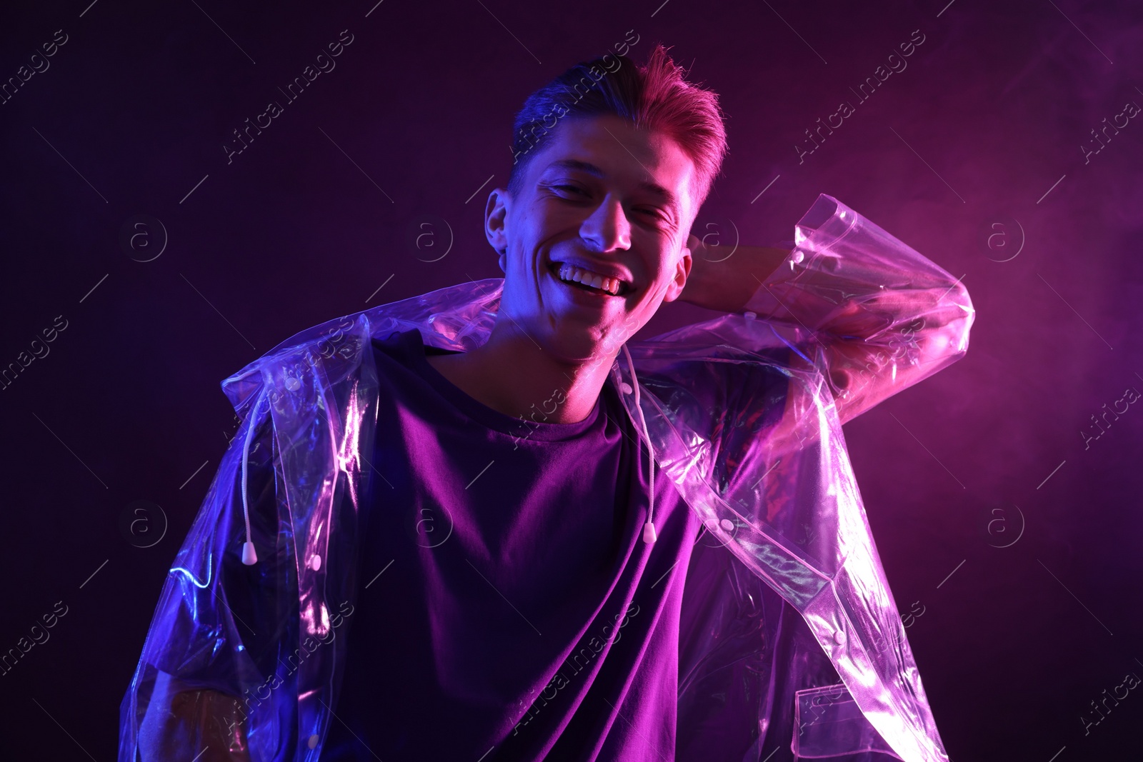 Photo of Young man wearing clear coat in neon lights with smoke effect