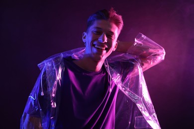 Young man wearing clear coat in neon lights with smoke effect