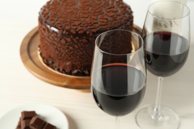 Photo of Delicious chocolate truffle cake and red wine on light table