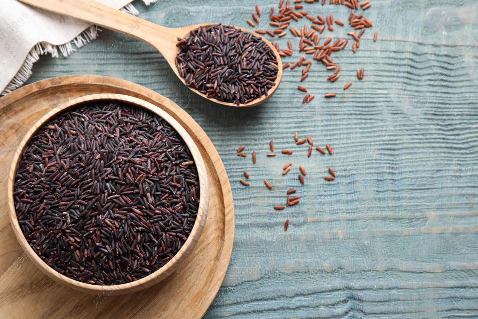 Photo of Brown rice on light blue wooden table, flat lay. Space for text