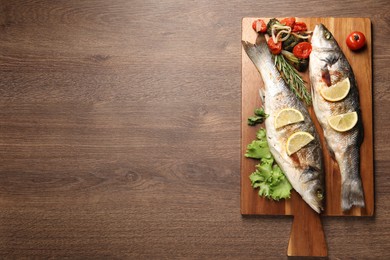 Photo of Delicious baked fish and vegetables on wooden table, top view. Space for text