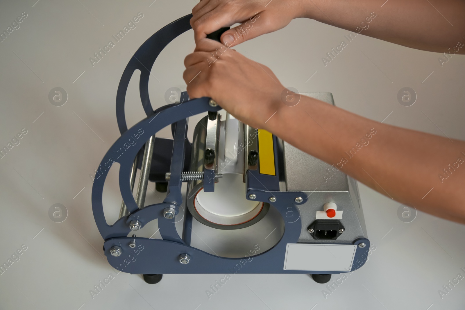 Photo of Printing logo. Woman with mug using heat press at white table, closeup